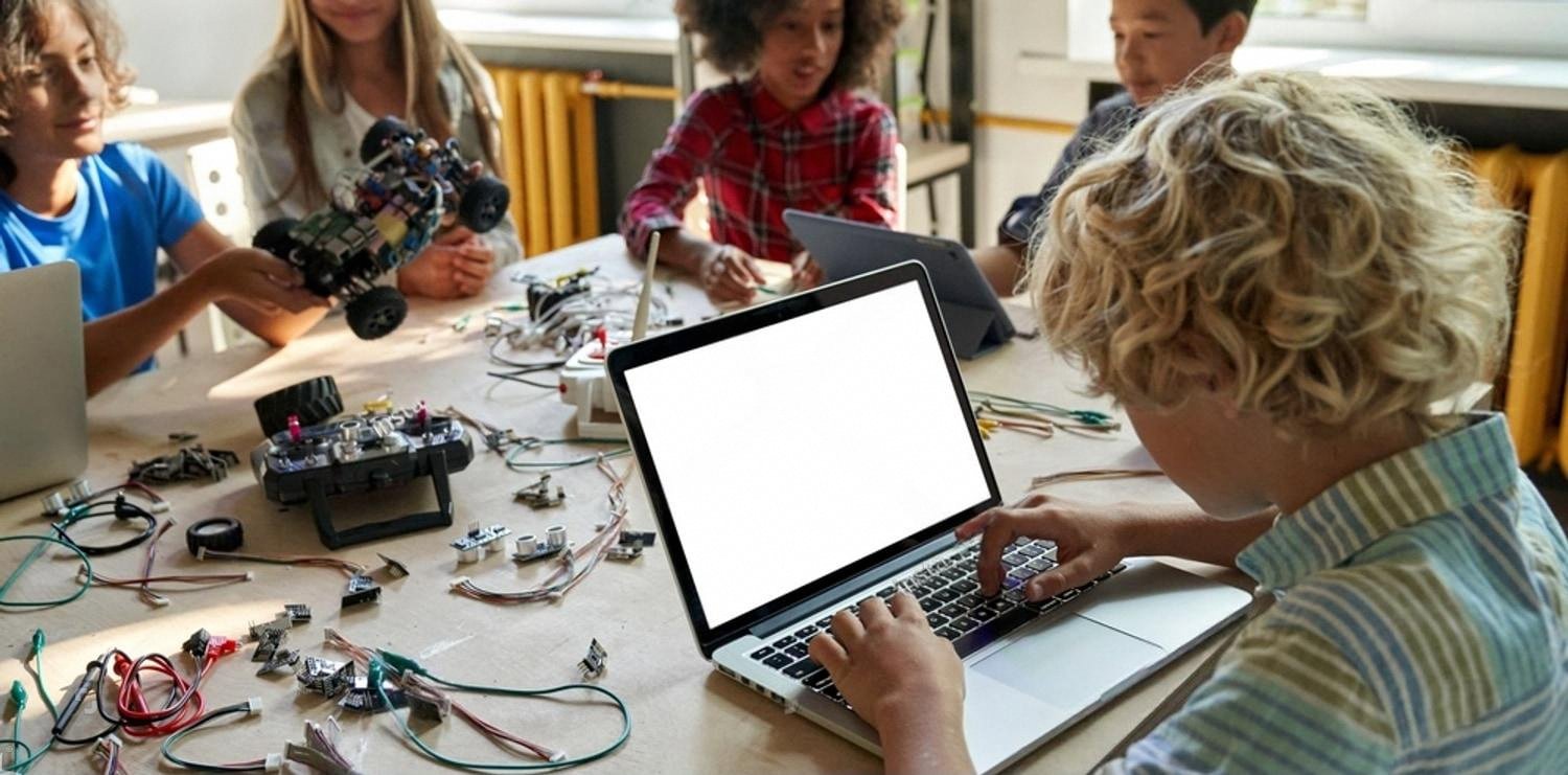 Group of children building electronics and coding on a laptop during a science and creativity class